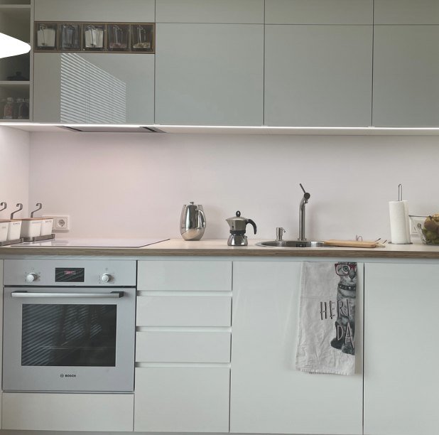 A tidy, light kitchen with a kettle and a moka pot on the counter